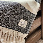 These Turkish throws have a stylish complex weave and are suited to use indoors and outdoors The incredibly soft hand-feel of these throws is truly luxurious! They are woven in a reversible black pattern and have a creme border complementing creme, and hand-spun tassels on the top and bottom edges. Large Throw: 55 inches X 78 inches 100% Turkish cotton