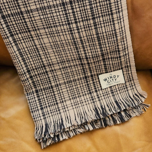 Snuggle up with our luxuriously soft Snickerdoodle Black Plaid cotton throw blanket! With its classic mid-weight flat weave design, this blanket is perfect for your couch or a decorative throw. The rich charcoal black stripes on the taupe background are bordered by soft eyelash fringe. Same pattern on both sides and made of 100% natural cotton, this throw is sure to bring comfort and luxury into your home.