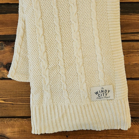 Made in the USA with a generous 52" x 64" size, it's perfect for staying warm by the fire and intricate, cable-knit design with hand knit finishes means it will be a staple in your living room. The cotton base and 15% plant fiber add an extra level of softness to this must-have snuggle companion!    